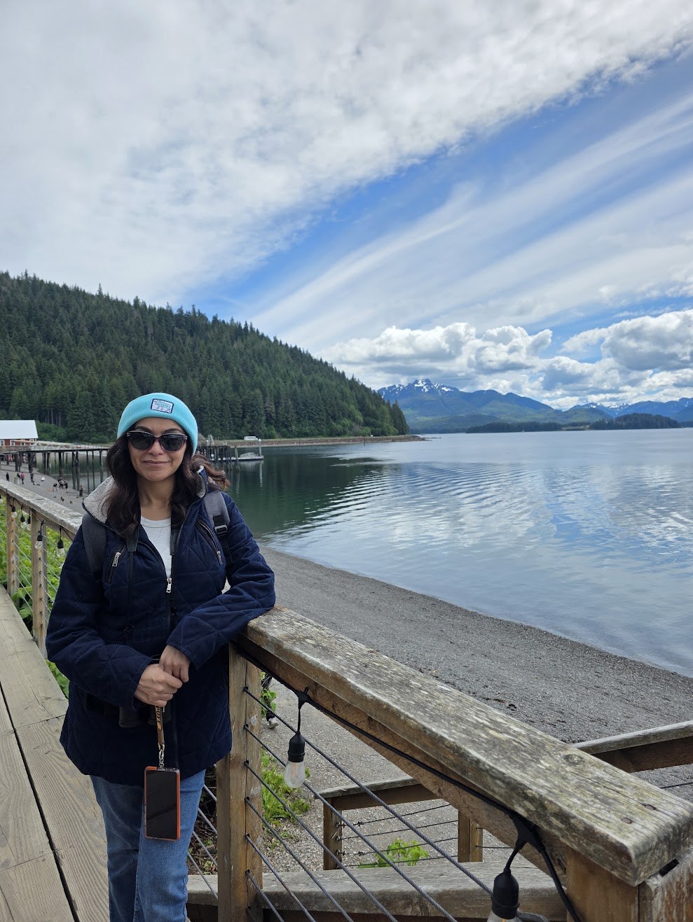 Traveler at an Alaska waterfront overlook with forested mountains across the bay