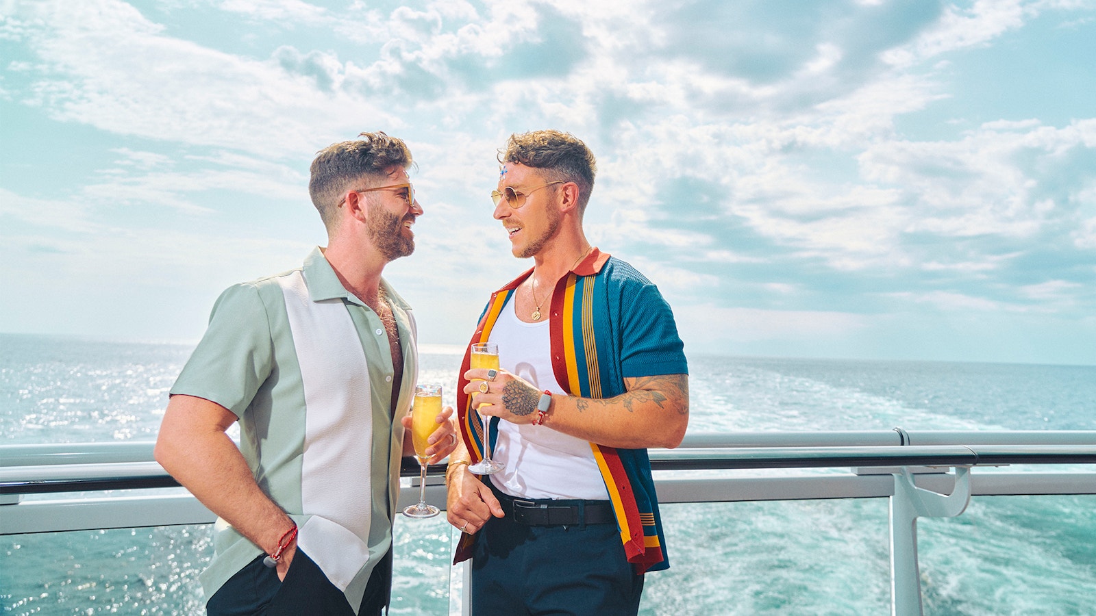 Two sailors celebrating Pride Month poolside with drinks